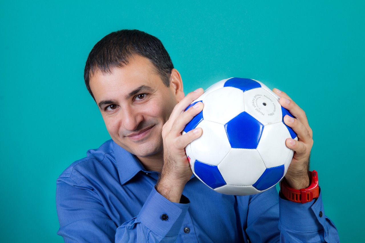 Middle-aged guy in a dress shirt smiling and holding a soccer ball