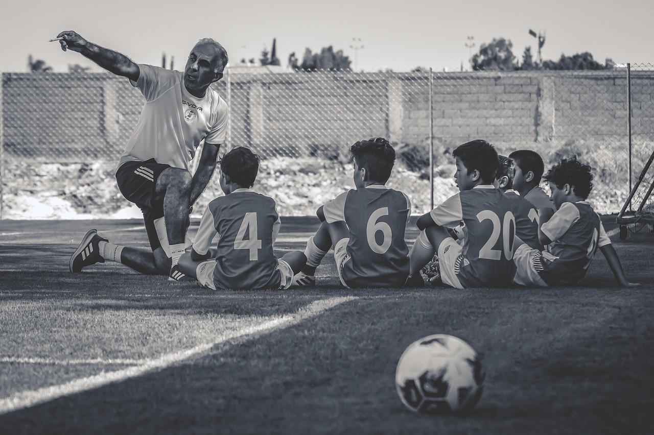 Soccer coach teaching young boys on the field