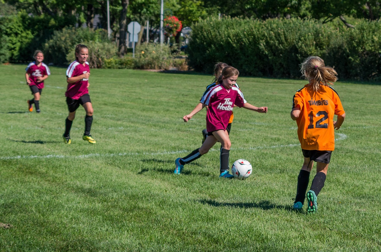 Young girls playing soccer on a grass field.