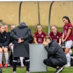 Coaches using a whiteboard to teach a female soccer team