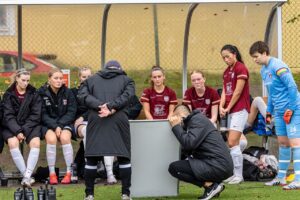 Coaches using a whiteboard to teach a female soccer team