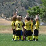 Very young soccer team surrounding coach and engaged and having fun