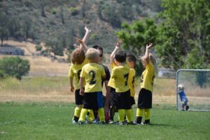 Very young soccer team surrounding coach and engaged and having fun